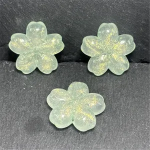 Closeup view of translucent green cherry blossom resin beads with gold glitter DIY accessories.