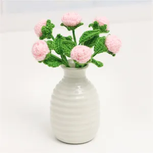 Detailed view of handmade crochet pink roses bouquet in ceramic vase, delicate mini floral decor.