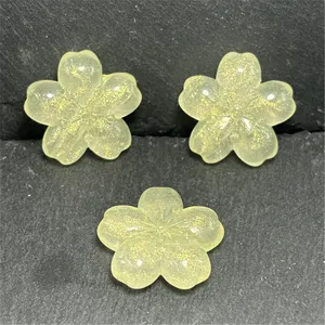 Close-up detail of translucent yellow resin sakura beads with gold glitter for DIY jewelry.