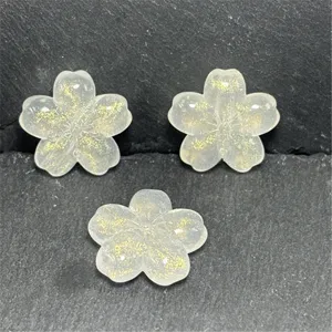 Detailed close-up of luminous cherry blossom beads with gold glitter for DIY crafts and jewelry