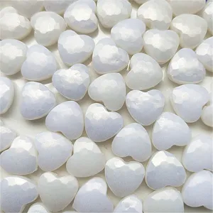 Close-up detail of glossy white iridescent heart acrylic beads for DIY jewelry making.