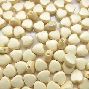 Detailed view of cream white heart shaped pearlized DIY jewelry beads for crafts and phone charms.