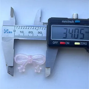 Detailed view of pink glitter bow bead DIY craft accessory measuring 34mm with caliper