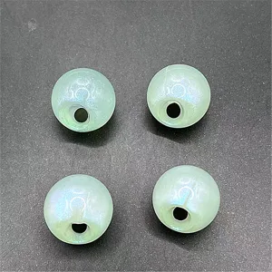 Gros plan de perles vert clair phosphorescentes à trou latéral pour créer des bijoux DIY.