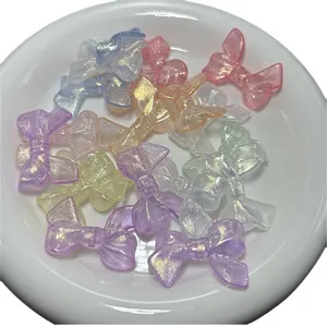 Acrylic glitter translucent bow beads in white plate for DIY phone charms and jewelry making.