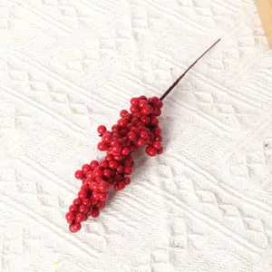 Close-up detail of artificial Christmas red berry branch, fake holly foam fruit for wreath decor.