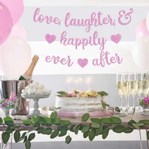 Dettaglio banner nuziale glitterato con lettere rosa brillanti e decorazione romantica.