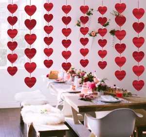 Detail view of red heart hanging garlands set up in a romantic party dining room scene decor.