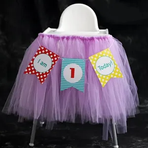 Purple tutu high chair skirt set with first birthday banner for baby party decoration setup.