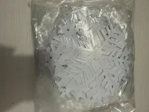 White plastic snowflake hanging decoration detail, closeup view of Christmas party window props.
