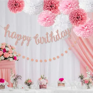 Rose gold happy birthday banner and paper pom poms party decorations set for celebration.