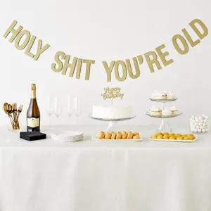 Mise en scène de décoration de fête avec bannière dorée, gâteau et diverses friandises.