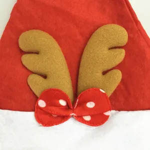 Close-up detail of Christmas hat with cute felt reindeer antlers and polka dot bow, festive decor.