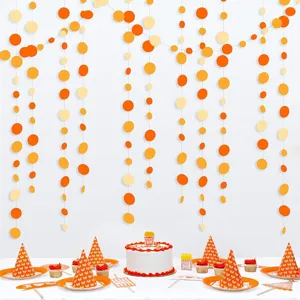 Orange paper dot garlands party decorations set with matching hats and cake toppers for birthday.
