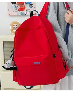 Detail view of a bright red school backpack with blue straps, front pocket, and cute plush octopus.
