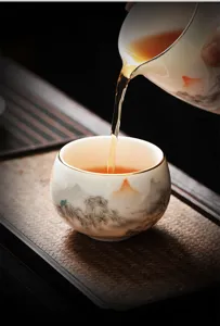 Vue detaillee de la tasse a the en ceramique et de la cruche avec motif de paysage.
