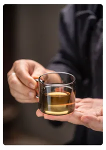 Tasse à thé en verre foncé pour dégustation, format miniature avec poignée, détail élégant.