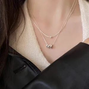 Silver double layer necklace closeup featuring geometric irregular ring pendant and dainty chain.