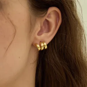 Close-up detail shot of shiny gold multi-layer hoop earrings worn elegantly on earlobe.