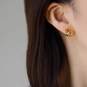 Close-up of elegant gold plated geometric wave ear studs worn on ear, detailed product shot
