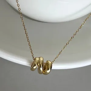 Detailed close-up of a stylish geometric irregular wave pendant necklace in gold brass.