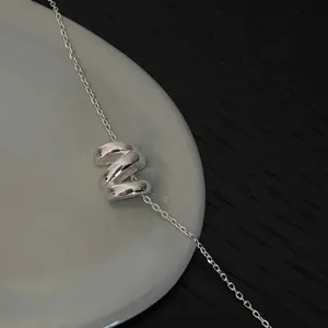 Detailed shot of silver-tone irregular wave pendant necklace, elegant geometric jewelry piece.
