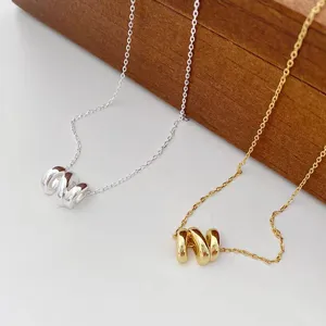 Elegant geometric wave pendant necklace in gold and silver, trendy everyday jewelry item.