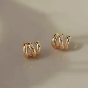 Exquisite triple-band wave gold-plated earrings detail shot, minimalist chic fashion jewelry style.