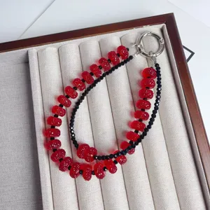 Red glitter beaded phone strap and bag charm detail, stylish double layer accessory.
