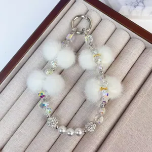 Chic plush crystal phone chain and stylish keychain featuring soft white pom poms.