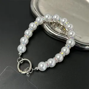 Close-up of elegant white faux pearl phone wrist strap with crystal rhinestone spacer beads.
