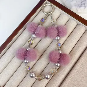 Close-up detail of fluffy pink plush balls and crystal bead phone chain keychain pendant.