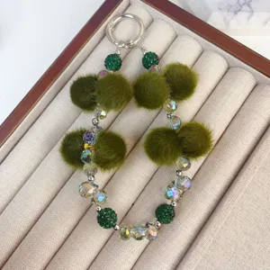 Detailed view of handmade green plush pom-pom crystal beaded phone charm and keyring strap.