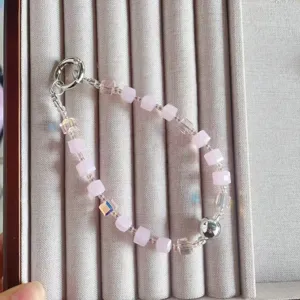Handmade crystal beaded phone wrist strap detail, pink square beads and silver charm, elegant.