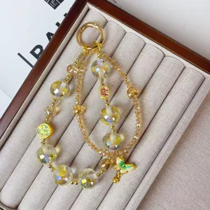 Detail view of crystal beaded phone chain and bag charm with gold alloy and lucky pendants.