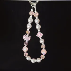 Close-up detail of pink crystal beaded phone charm with a sparkling bow zircon.