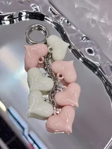 Resin heart keychain detail view, glossy pink and white charms with metal ring and chain.