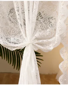 White lace curtain detail closeup with delicate floral jacquard patterns and elegant pearls.