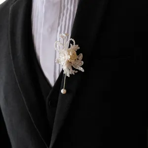 Detailed close-up of a white lace pearl boutonniere pin elegantly styled on a black suit lapel.