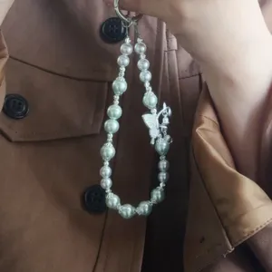 Detail view of the elegant pearl and crystal phone charm with a cute butterfly pendant accessory.