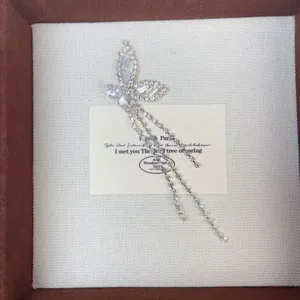Detailed close-up of sparkling rhinestone butterfly pendant with delicate chain tassels, elegant design.