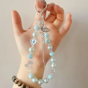 Close-up detail of the light blue beaded phone charm featuring a sparkling rhinestone bow.