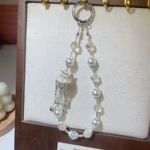 Close-up detail of luxury crystal pearl beaded wrist strap and charming phone charm pendant.