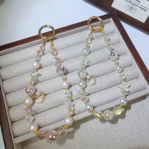 Detailed shot of handmade pearl crystal beaded phone chain with cute marine charms and rings.
