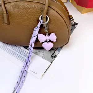 Morandi color bag pendant detail showing purple bow, heart charm and braided rope.