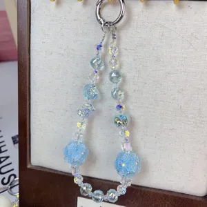 Close-up detail of light blue crystal beaded phone and bag charm with rose flower balls.
