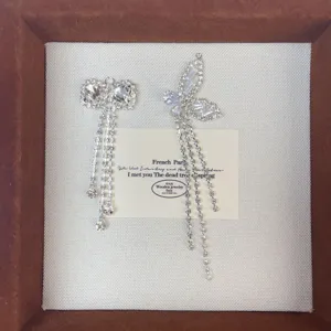 Rhinestone bow and butterfly tassel earrings detail view, sparkling silver jewelry accessories.