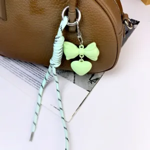 Close-up detail of the cute light green bow and heart bag charm with braided rope.