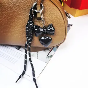 Chic black bow and heart bag charm with braided rope keychain for stylish accessories.