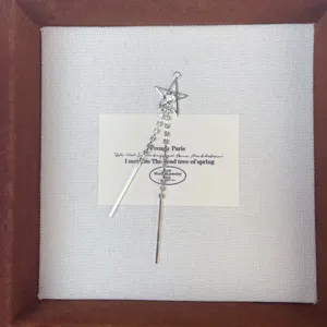 Silver star rhinestone tassel earring detail display on white card inside jewelry box.